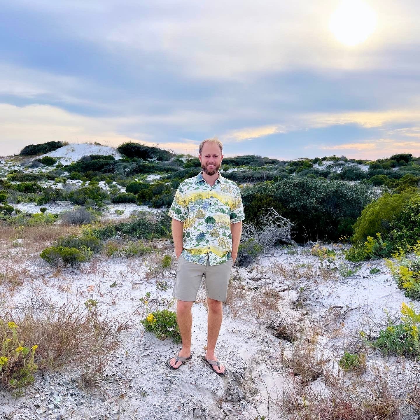 A man wearing the Coastal Dunes Floridian Shirt by Okihasi standing next to Coastal Dunes in Northwest Florida.