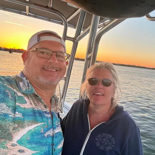 A man and a woman on a boat. The man is wearing the Barrier Island Floridian Shirt by Okihasi.